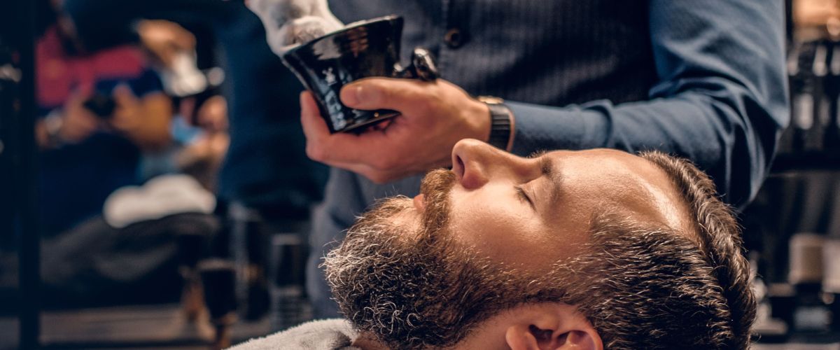 Relaxing man gets a shave from a barber who knows his style.